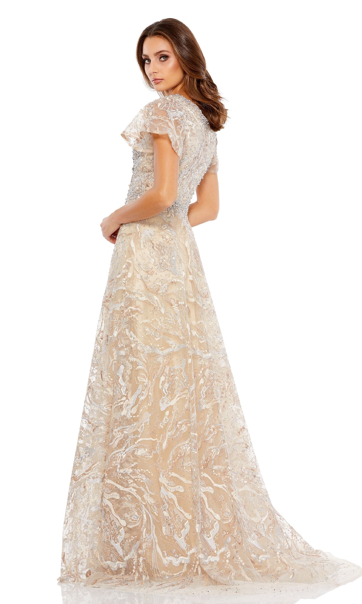 A woman wears the Mac Duggal 20301 short-sleeve formal dress in light beige, featuring a beaded waist, as she glances over her shoulder against a plain white background.